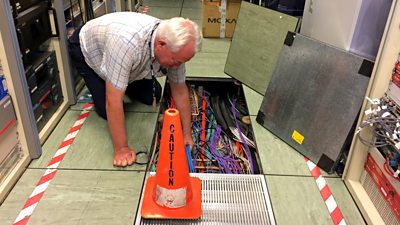 technician looking at cables under floor panel