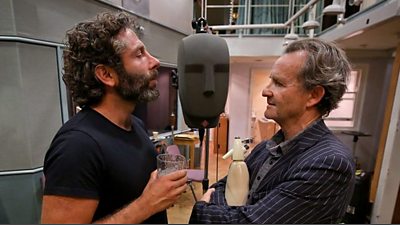 Two actors stand at both sides of a binaural head microphone.