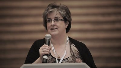 Clare McGinn on a stage holding a microphone