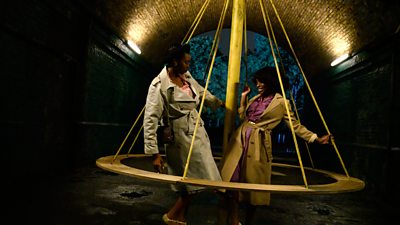 A couple dance around a swing in an underground vault