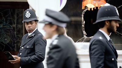 A black policeman stares at a colleague