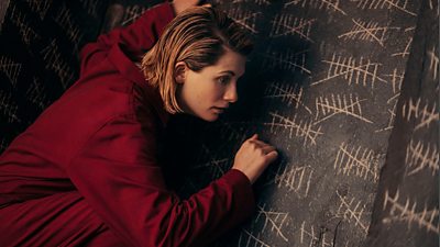 The Doctor (Jodie Whittaker) taps against a wall covered in tally marks