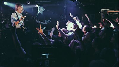 Paul McCartney on stage at a secret gig at The Cavern Club in Liverpool in July 2018, fans face him with their arms in the air