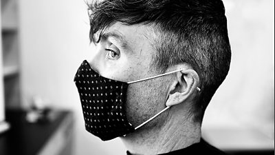 Black and white image of Cillian Murphy in profile wearing a facemask in the makeup chair