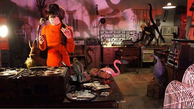 Delia Derbyshire (Caroline Catz) at the decks in a room decorated in a kitsch style