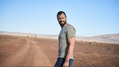 Actor Jamie Dornan stands alone on a dirt road