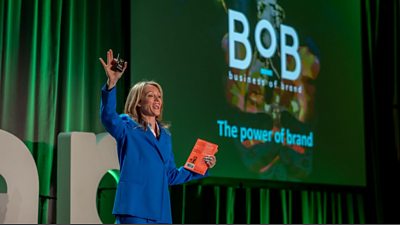 BoB Earth founder Linzi Boyd presenting from a stage with a screen behind that says "BoB business of brand The power of brand"