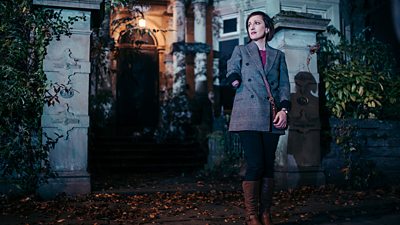 Nadia Albina stands outside a house on a dark road in Doctor Who