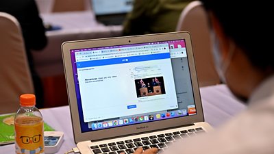 Over the shoulder photograph of a man looking at a laptop screen with AFP at the top of the screen