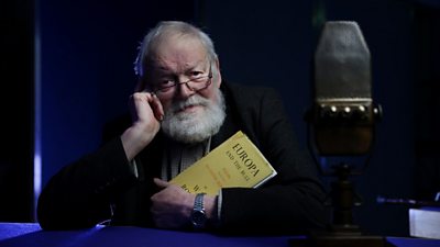 Michael Longley holds a copy of Europe and The Bull and is pictured behind a radio microphone