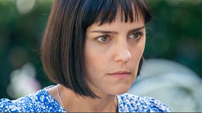 Annabel Scholey as Ann-Marie Blake who has bobbed brown hair and wears a blue and white patterned top