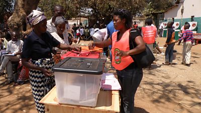 A woman places her vote in a box