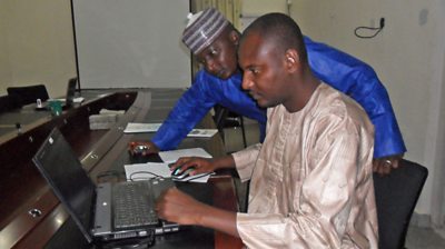 Journalist Aliyu Misau showing his colleague the skills he learned during BBC Media Action training.