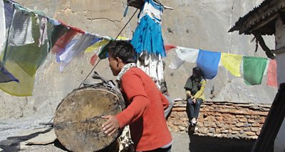 A man calls the villagers to gather for the Climate Asia community assessment by beating his drum.