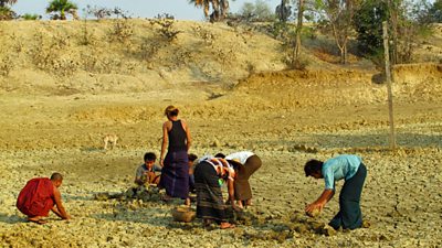 A group of people digging a dry pond bed in an arid landscape