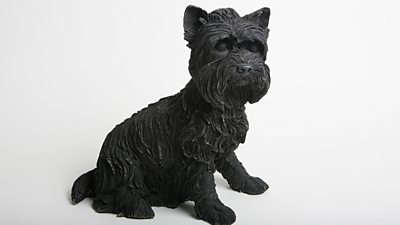 A small black model of a terrier dog. 