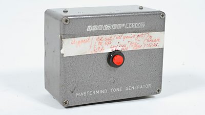 A handmade looking metal box with a big red button in the centre. The text says 'Mastermind tone generator'