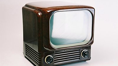 A brown cuboid television set with a two dials on the front. 