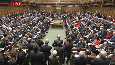 The House of Commons recorded for television - the house is full of MPs sitting on opposing sites. A caption with 'live' is in the top left. 