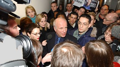 Greg Dyke is surrounded by journalists, camera operators and 鶹Լ staff. Once holds a sign saying 'bring back Greg'. 