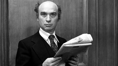 Ken Campbell in a suit reading a newspaper