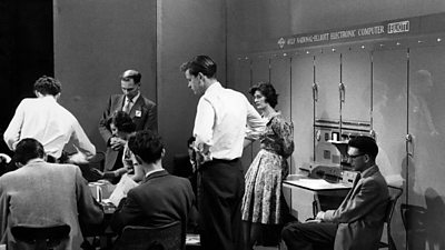 A group of people gathered around a giant computer. 