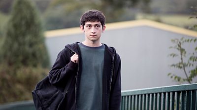 A young man walks dreamily along a footpath