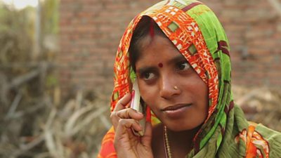 Young mother listening to Mobile Kunji through her mobile phone