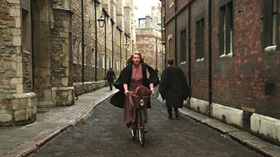 Sylvia Plath, wearing a gown, cycles up a narrow Cambridge Street