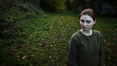 A young girl looks frightened in an autumnal path. 