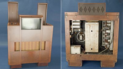 A huge brown almost square cabinet with a large speaker, a square television screen rising slightly above the rest of the box at the top. Two panels of controls are open. Inside are a variety of valves and wires.