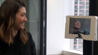 A woman looking at a telepresence robot