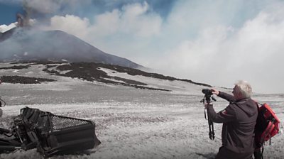 Man in front of a volcano.