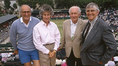 Four people standing on a balcony overlooking Centre Court