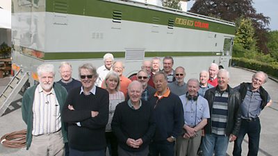 Veteran Crew Group Shot. 19 people stand in front of a large rectangular scanner van with 鶹Լ tv colour on the side. 