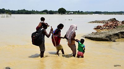 A Nepali family make their way through flood waters in Tilathi Village in Saptari District.
