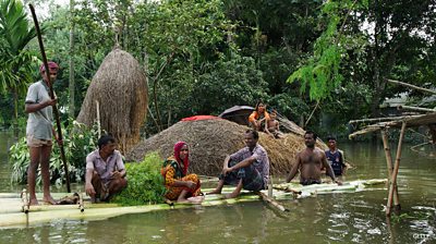 Bangladeshi stand on a raft made of banana tree trunks in an area submerged by flood in Kurigram, northern Bangladesh on August 14, 2017.