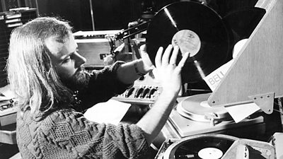 A long-haired John Peel pulls a record from a sleeve