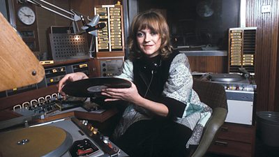 Annie Nightingale poses with a record above a player in the studio