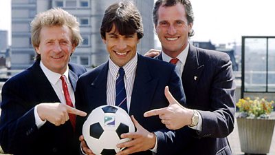 Two men point at a football held by John Inverdale - the football has a Radio 2 logo on it. 