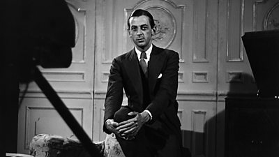 Alistair Cooke, looking very young, in a smart suit