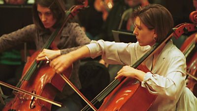 Two female cellists in an orchestra.