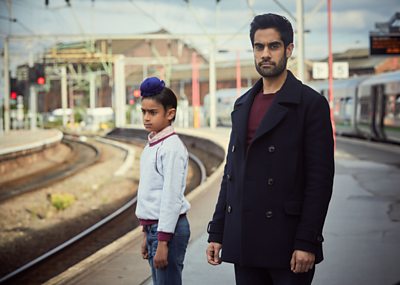 Young Sathnam (HIMMUT SINGH DHATT), Sathnam (SACHA DHAWAN) Image Credit: BBC/Parti Productions & Kudos