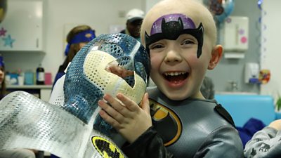 William holds his Batman mask