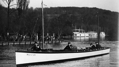 A long, thin white boat with a radio antenna between two large masts. Four technicians are aboard.