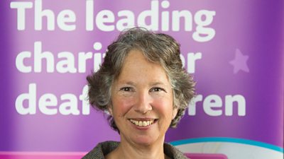 Susan Daniels in front of a charity banner 