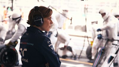 Claire Williams looks pensive in the pit lane wearing ear protector headphones