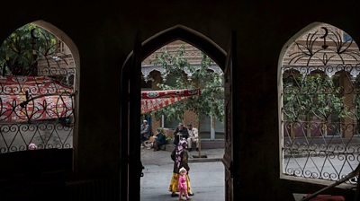 An Uighur woman walks by the closed Islamic school in Xinjiang