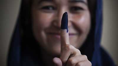 Woman showing inked finger after voting