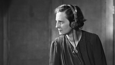 Muriel Howlett, wearing headphones, looks wistfully away from the camera.